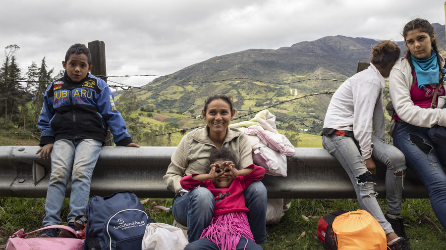 A family sits on the side of the road with their belongings