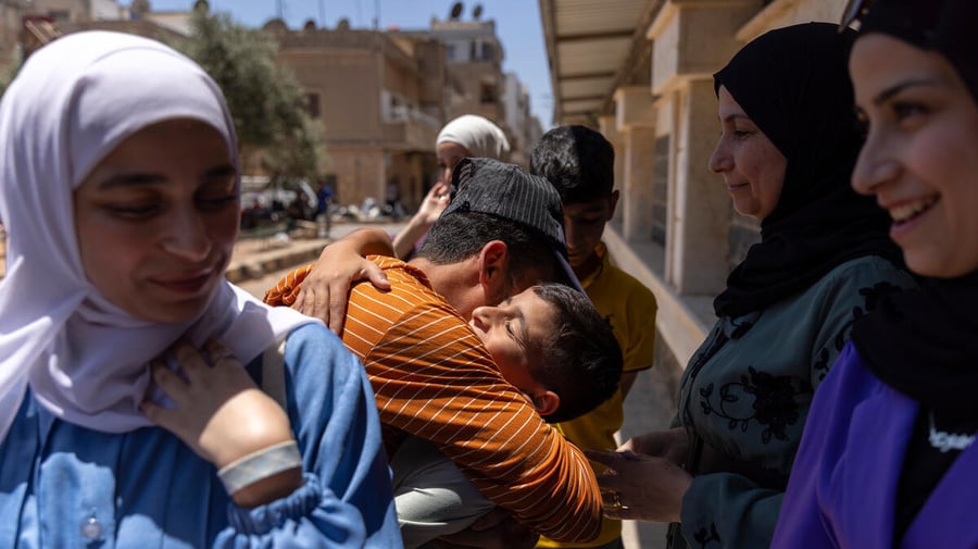 A Syrian family embraces, with others smiling nearby
