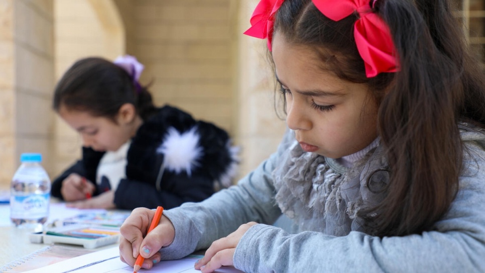7 歲的 Mais（左）和 9 歲的 Marah（右）在約旦馬達巴的社區中心畫下她們印象中的敍利亞。© UNHCR/Lilly Carlisle