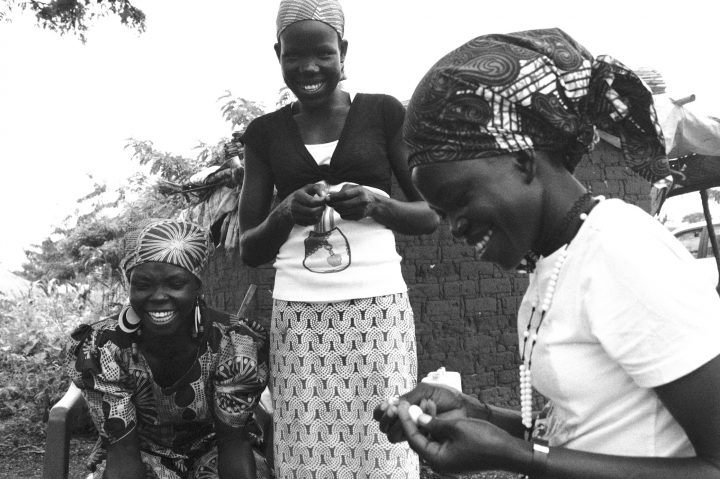 Three refugee women from South Sudan share a laugh near the salon they opened in Uganda