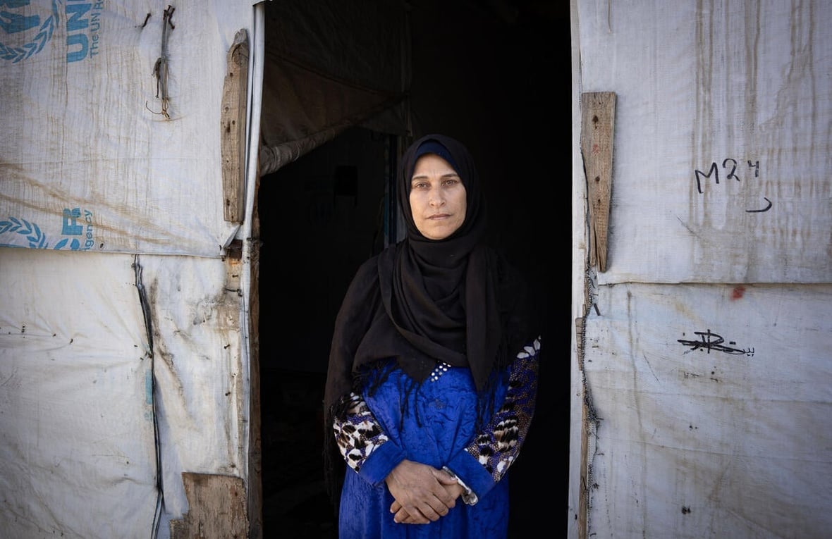 شاديا جاسم، 50 عاماً، تقف عند مدخل خيمتها في مخيم الياسمين في بلدة سعدنايل في لبنان. 
