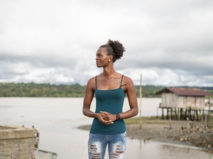 A trans woman stands on the banks of a river in Colombia's Chocó Department.