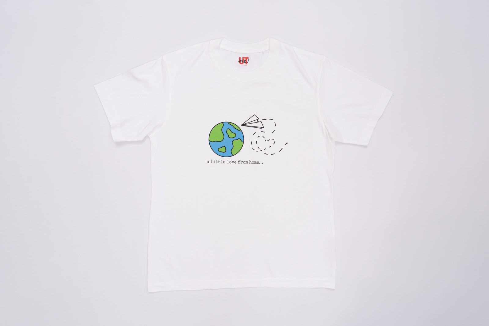 A white t-shirt with an illustration of the Earth and a paper plane flying around it