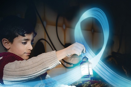 A young boy is holding a small lantern in a dark room. A blue, shiny and flying ribbon floats around the lantern.