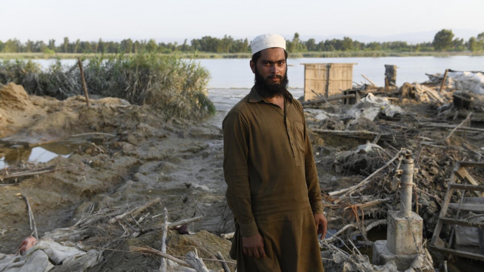 Saleem Khan, a 25-year-old farmer, stands where his house once stood before being washed away by floods. © UNHCR/Usman Ghani