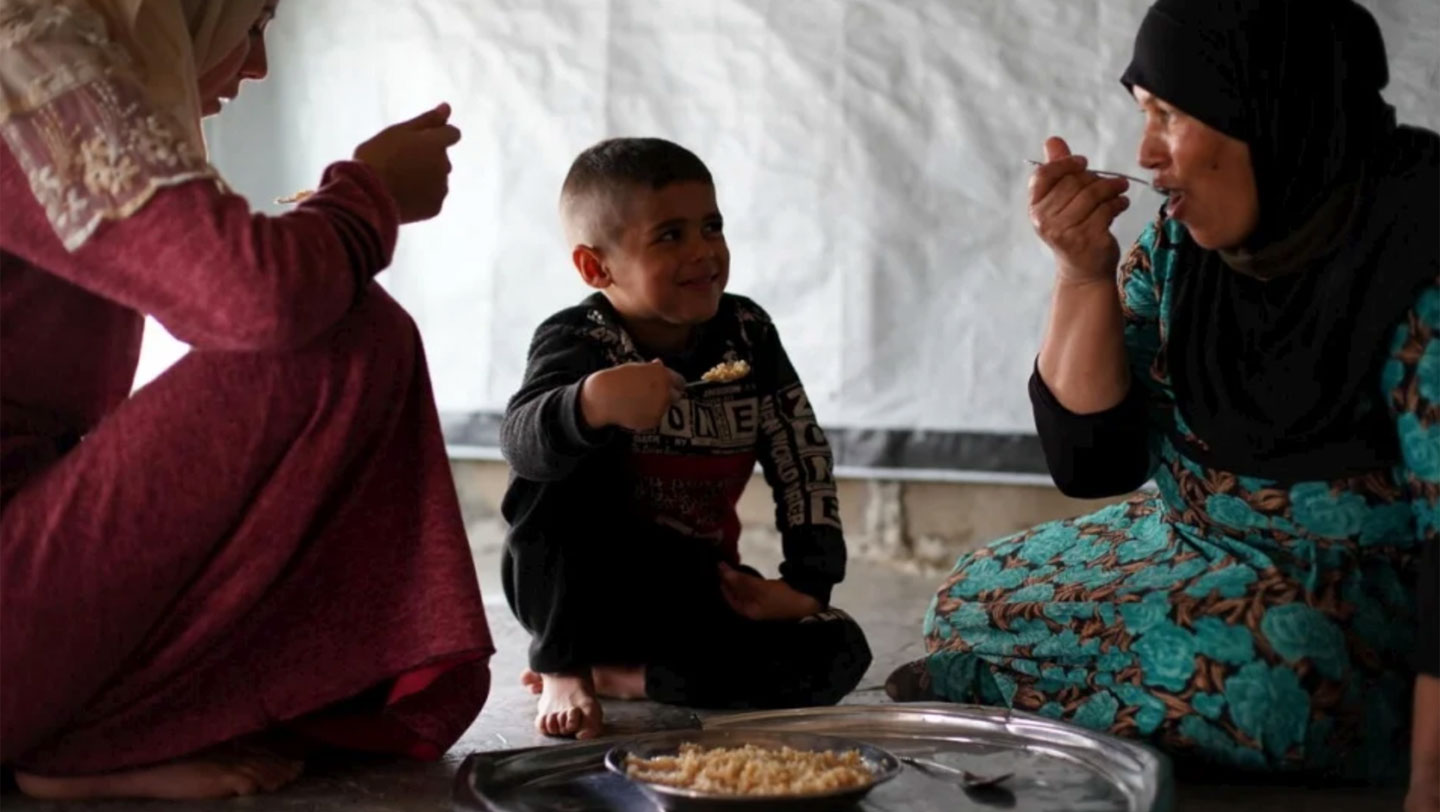 Khadra shares a meal with her daughter-in-law and nephew inside the one-room tent that shelters her and nine other family members. © UNHCR/Joelle Abou Chabke