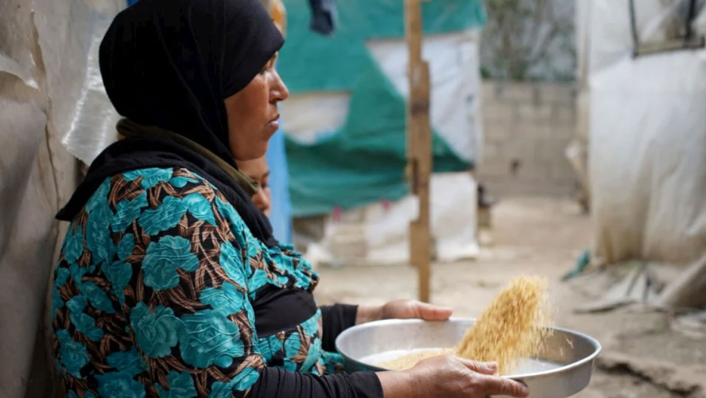 Khadra cleans lentils outside her tent. © UNHCR/Joelle Abou Chabke