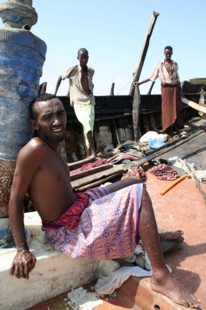 Des Somaliens et des Éthiopiens récemment arrivés se remettent de leur périple, assis dans le bateau des passeurs, que les forces armées yéménites ont intercepté et forcé à accoster. Les passeurs ont pris la fuite à bord d'un canoë à moteur.