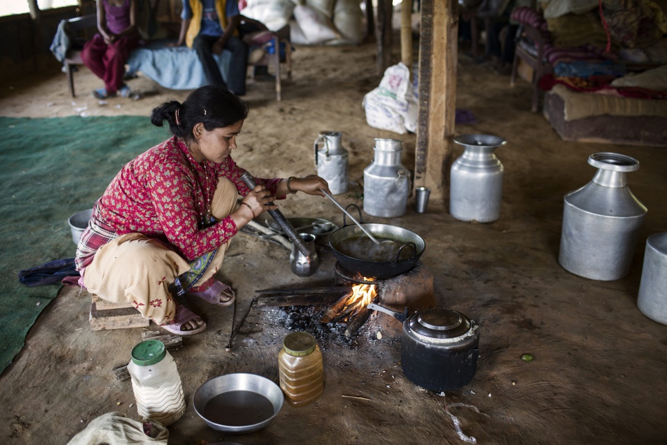 Gauri, 30, prepares food at her temporary shelter in Nepal which she built using a UNHCR tarpaulin after her family home was destroyed by an earthquake in 2015. She and her husband are hosting another five families who live in an area they use to raise chickens.