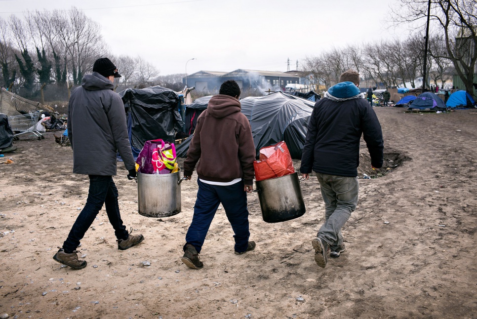 Volunteers carry food to Tioxide, an encampment named for a nearby chemical plant.