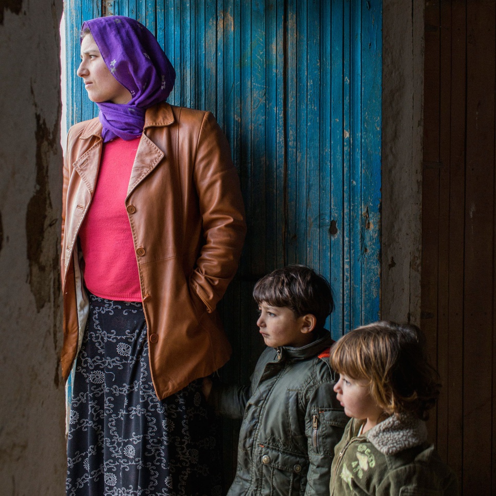 With her two eldest children at her side, Dozgeen, 24, looks homeward from her family's temporary refuge in Saygin, Turkey.