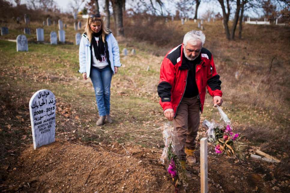 Akis and Sia Armpatziani clean the grave of 6-year-old Rand Al-Hayek from Syria during the family's last visit.