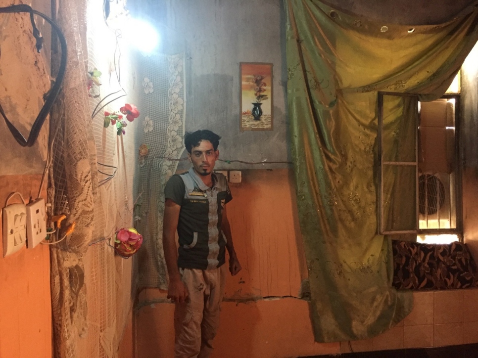 يقف إبراهيم خليل، 25 عاماً، عامل وسائق رافعة، ، داخل إحدى الغرف المتضررة في منزله في الرمادي، العراق.