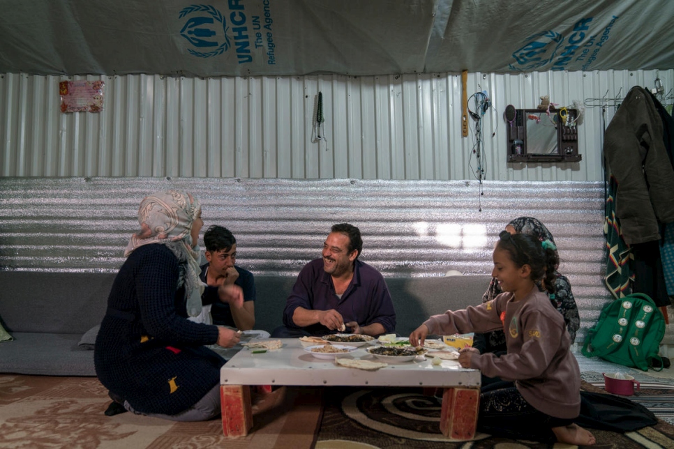 اللاجئ السوري إحسان الخليل وزوجته رباب وثلاثة من أولاده يتناولون الغداء في مسكنهم في مخيم الأزرق للاجئين في الأردن.