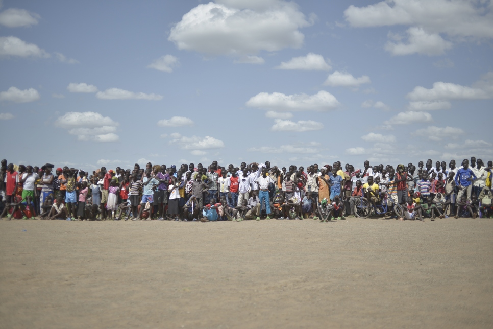 Des résidents de Kakuma regardent sur grand écran la retransmission de l'événement TEDxKakumaCamp hors de la tente-entrepôt. 