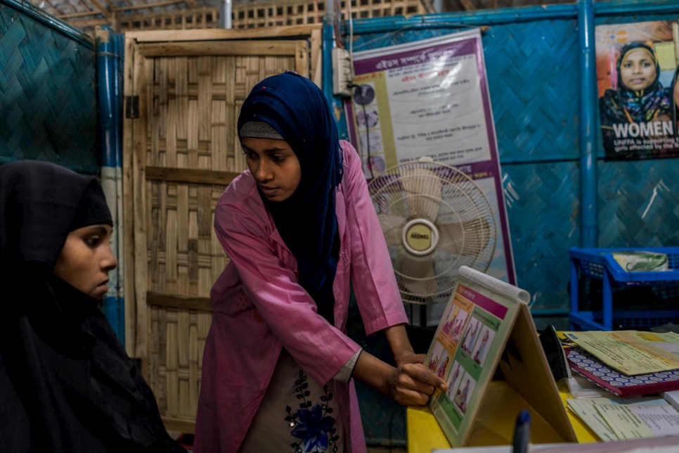 القابلة شيرين أكتر، البالغة من العمر 21 عاماً، تعلم روميدا بيغ، البالغة من العمر 25 عاماً، وهي امرأة من الروهينغا حامل وأم لطفلين، عن صحتها خلال فترة الحمل في مرفق للرعاية الصحية الأولية تموله المفوضية وصندوق الأمم المتحدة للسكان في بنغلاديش. 