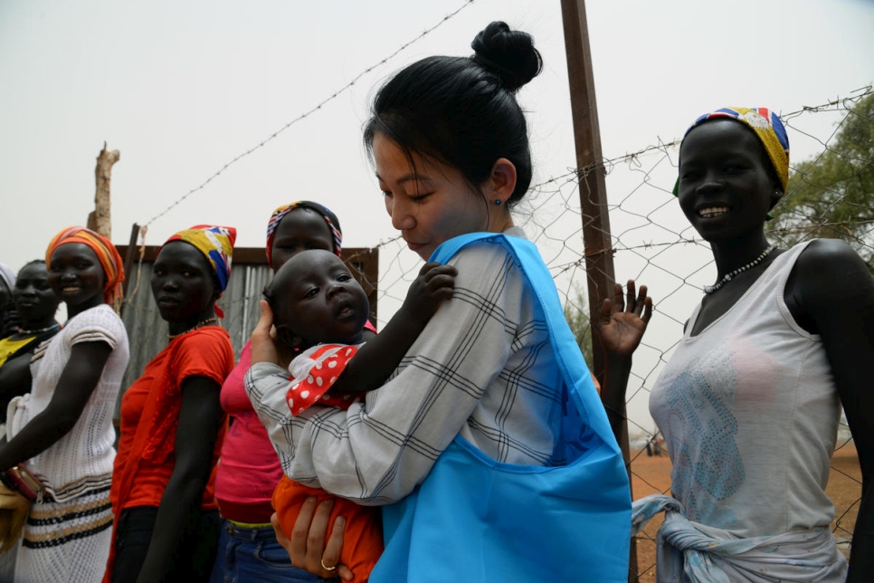 مسؤولة الاتصال في المفوضية يوجين بيون تحمل طفلاً لاجئاً في مخيم في جنوب السودان.