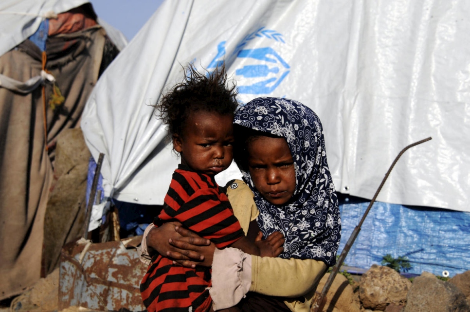 Déplacés du gouvernorat de Taïzz depuis le début du conflit, Rahaf, 8 ans, tient son frère Ahmed, 2 ans, dans les bras devant la tente familiale à l'installation de Dharawan au Yémen. Mai 2017. 