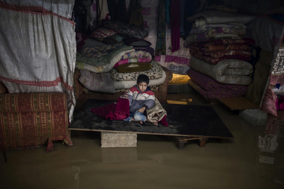 أحد أطفال جورية رمضان يجلس داخل خيمته المغمورة. انهارت الخيمة نتيجة لعنف العاصفة نورما.