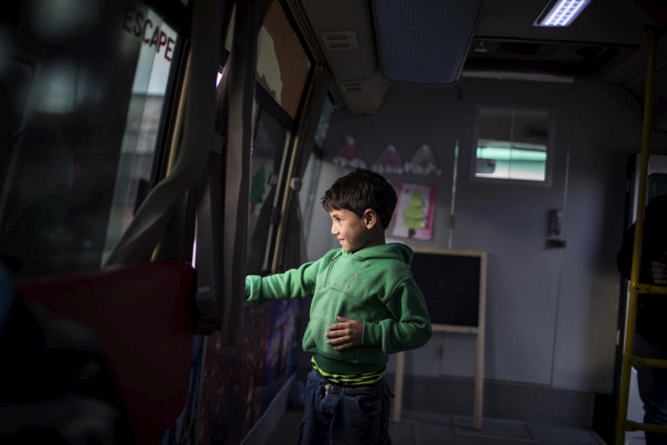 ينظر عزو، وهو طفل سوري لاجئ من حلب ويبلغ من العمر ست سنوات، عبر نافذة "حافلة المرح". 