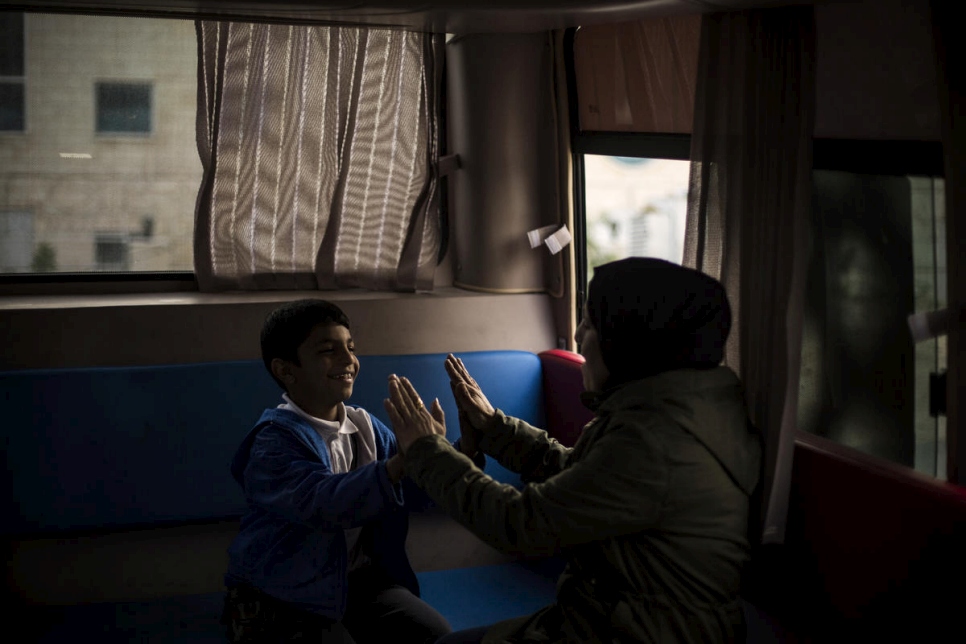 فتى سوري لاجئ يلعب مع إحدى المتطوعات على متن "حافلة المرح".