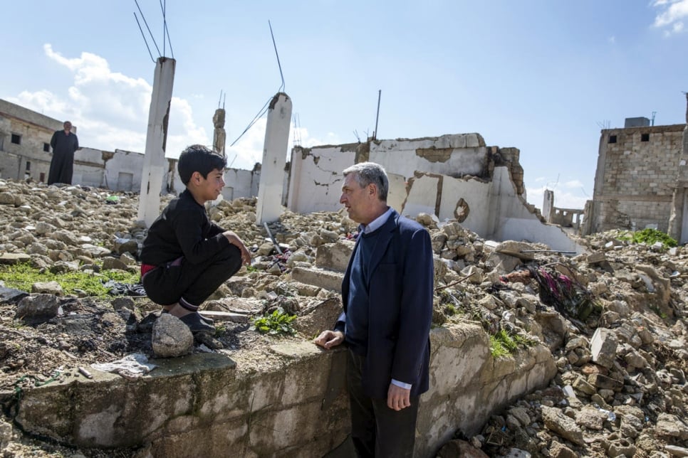 Dans la ville de Souran et au milieu des décombres, le chef du HCR Filippo Grandi s'entretient avec un jeune rapatrié.  