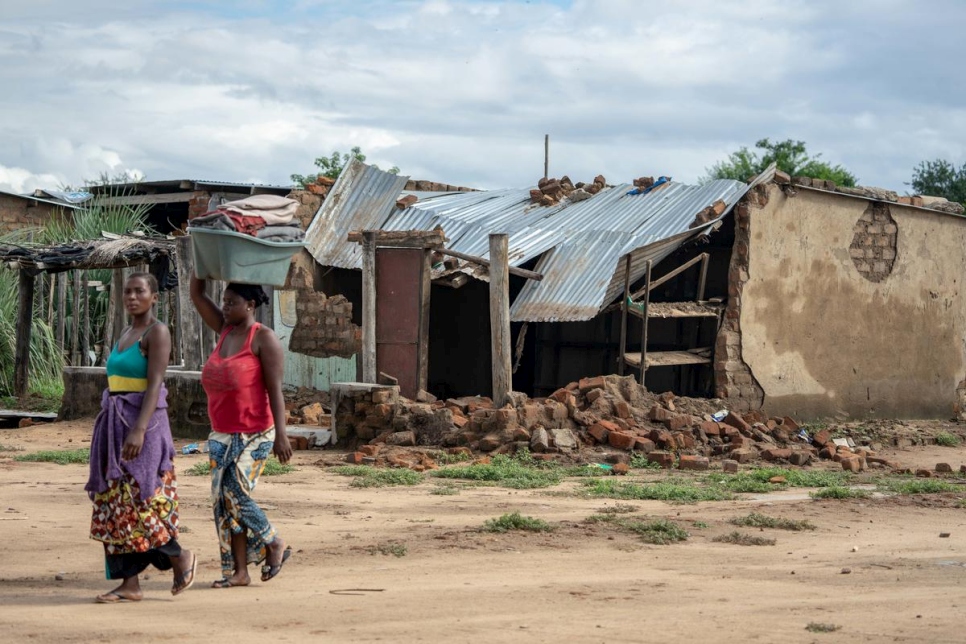 امرأتان تسيران أمام منزلٍ تدمر في انزلاقٍ للتربة نتيجة إعصار إيداي في مخيم تونغوغارا للاجئين في تشيبينغ، جنوب شرق زيمبابوي.