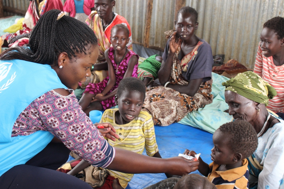 Millicent Lusigi (left) gives a young refugee boy some plumpy nuts at the nutrition centre in Kule camp, Ethiopia.