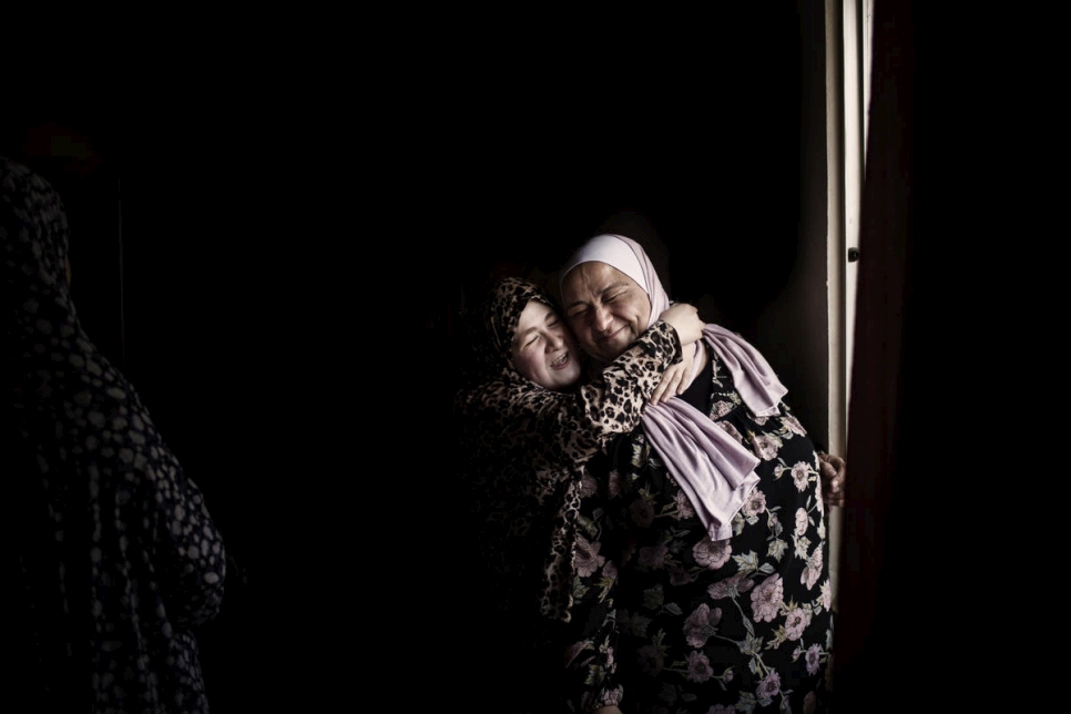 ابنة اللاجئة السورية هيفاء الدلال تعانق عبير خريشة أثناء زيارتها لمنزلها في مأدبا، الأردن.  