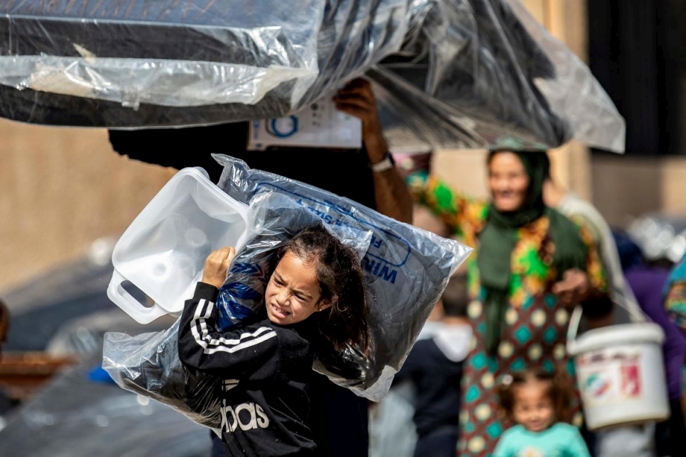 Syria. Young girl displaced by recent violence carries relief supplies