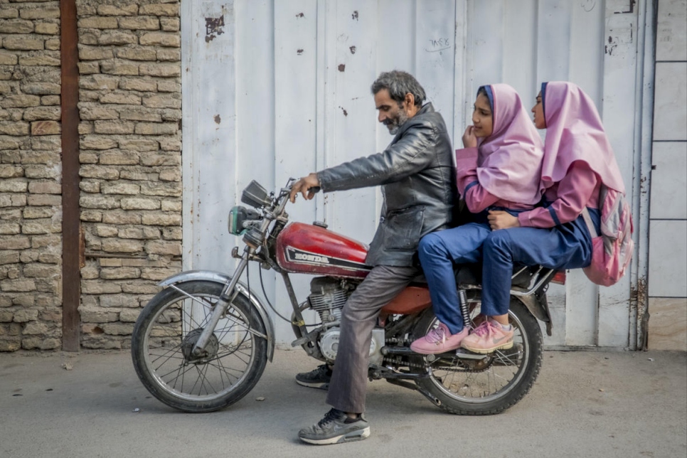 اللاجئ الأفغاني بسم الله يقود دراجته مع ابنتيه باريسا وباريما في طريقهم إلى المدرسة، على بعد 10 كيلومترات من منزلهما في أصفهان، إيران.