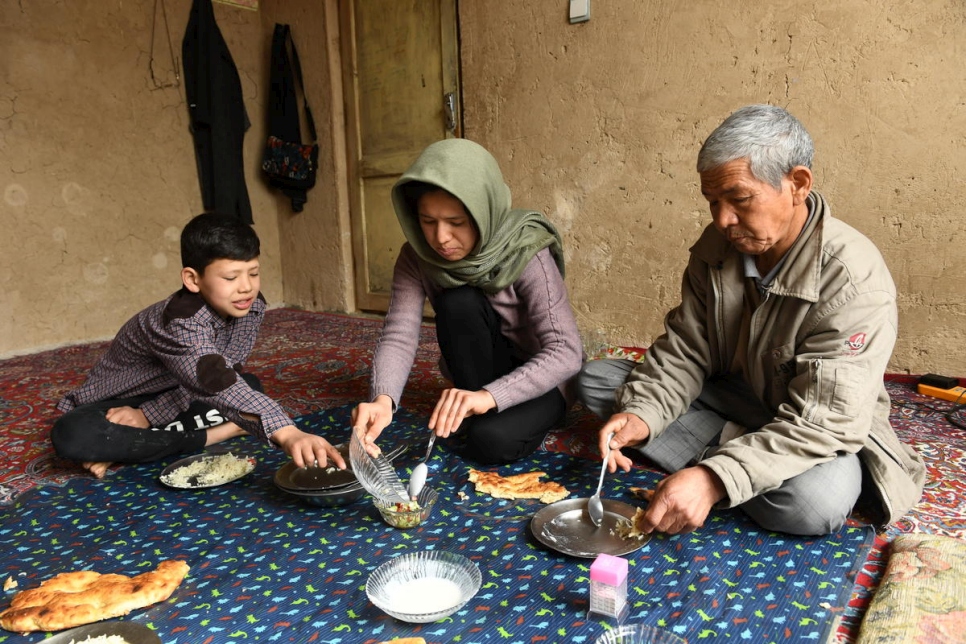 العائدة الأفغانية كوبرا يوسفي تتناول طعام الغداء مع شقيقها مهدي ووالدها محمد، في غرفة الجلوس في كابول. 