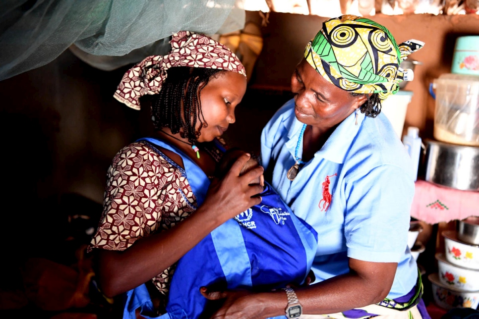 Une femme aide Absatou pour installer son bébé contre elle en « peau-à-peau » grâce au foulard de la méthode kangourou au centre de santé de Mbile. Depuis qu'elle a fui la République centrafricaine, elle a déjà perdu deux bébés nés prématurément. 