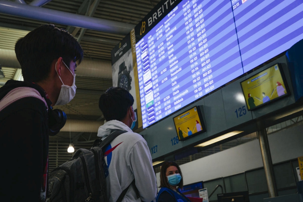 Deux mineurs non accompagnés regardent le panneau des départs à l'aéroport d'Athènes, avant d'embarquer à bord d'un avion spécialement affrété vers le Luxembourg dans le cadre d'une nouvelle initiative de relocalisation menée par l'UE. 
