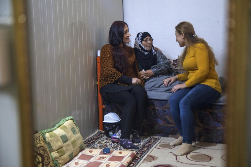 La réfugiée syrienne Falak Selo (à droite) parle à sa mère et à sa soeur dans le camp d'Akre, au nord de l'Iraq, où elle apporte un soutien en matière de santé mentale à d'autres réfugiés (26 janvier 2020).  