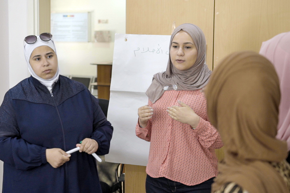 اللاجئات السوريات نبيلة (إلى اليسار) وسورة، تتبادلان الأفكار حول معالجة العنف القائم على نوع الجنس مع مجموعة مجتمعية أسساها في عمّان، الأردن.