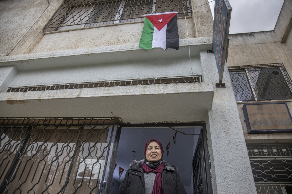 ريا الكباشي تقف تحت علم الأردن خارج المركز الصحي في إربد حيث تلقت لقاح فيروس كورنا.