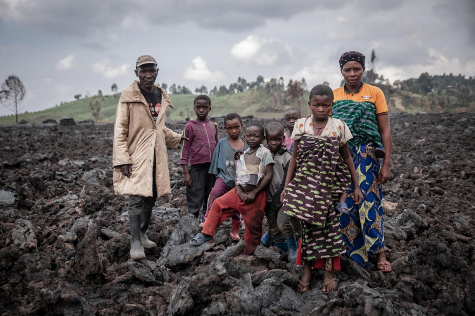 Jean et Esperance Muhoza et leurs sept enfants se tiennent sur la roche volcanique à l'endroit où se trouvait leur maison.