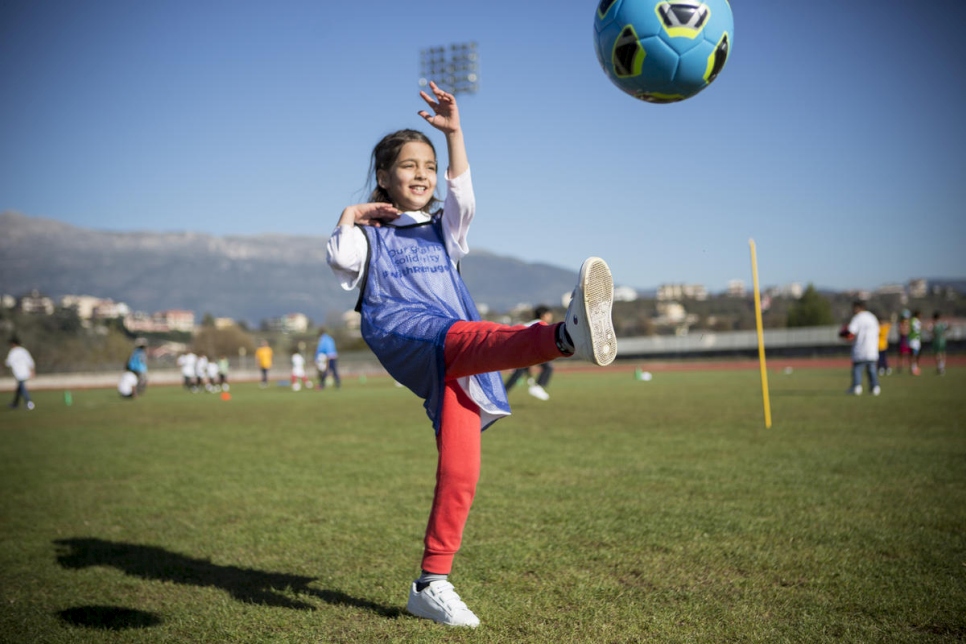 Une fillette envoie un ballon au pied durant un événement de solidarité envers les réfugiés. Des associations nationales de football à travers l'Europe s'engagent à contribuer à l'insertion des réfugiés dans leurs nouvelles communautés. 