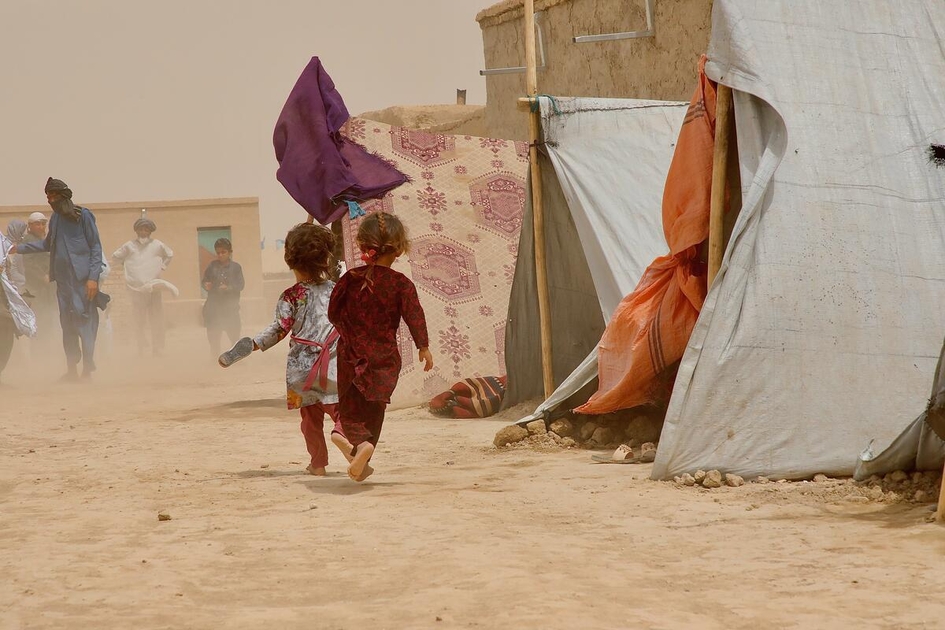 Children running to take cover as the heavy dust and the wind pierce through the Nawabad Farabi-ha IDP camp.