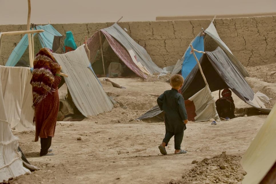 A woman and child walk between the makeshift tents in Nawabad Farabi-ha camp for internally displaced people in Mazar-e Sharif in northern Afghanistan.