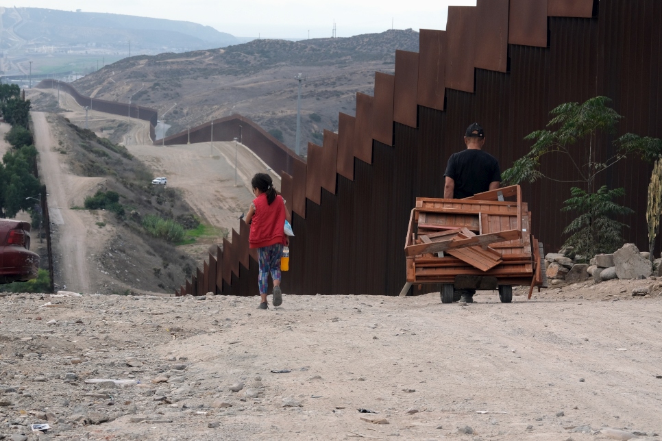Des personnes non identifiées longent la clôture marquant la frontière entre les États-Unis et le Mexique à Tijuana, au Mexique.   