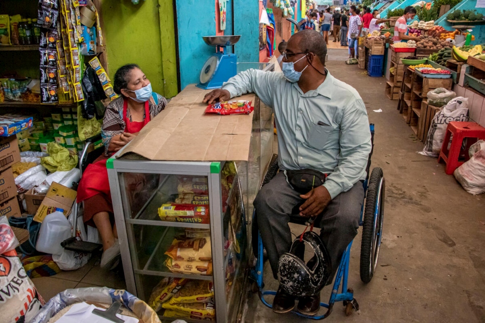 Omar, un réfugié colombien handicapé, discute avec une femme handicapée au marché municipal d'Esmeraldas, en Équateur, avril 2021