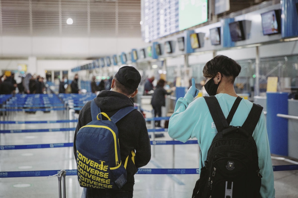 Deux enfants réfugiés afghans non accompagnés se préparent à embarquer sur un vol de relocalisation vers la France à l'aéroport international d'Athènes.  