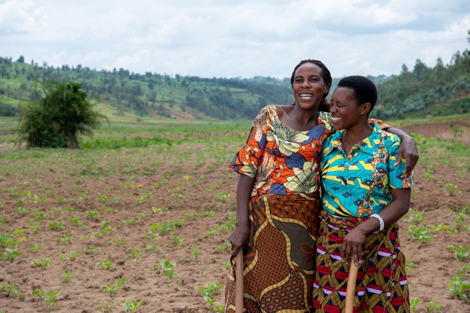 اللاجئة الكونغولية كليمنتين (إلى اليسار) وصديقتها الرواندية ياسين تقفان في أحد الحقول في رواندا.