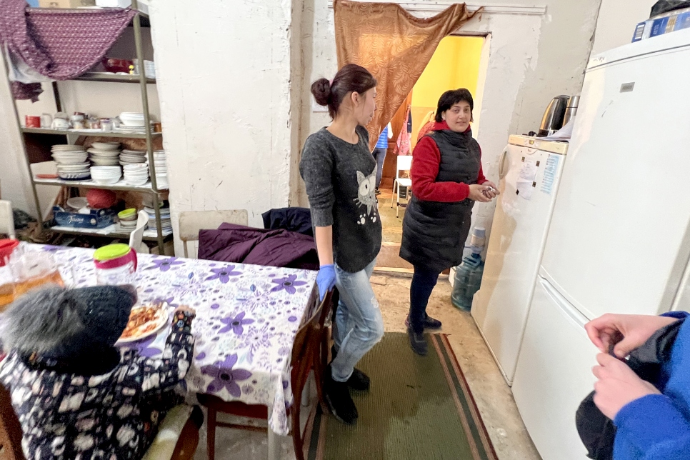 ريما ومتطوعة تساعدان في تنظيم وجبة في غرفة الطعام المشتركة في المأوى الجماعي.