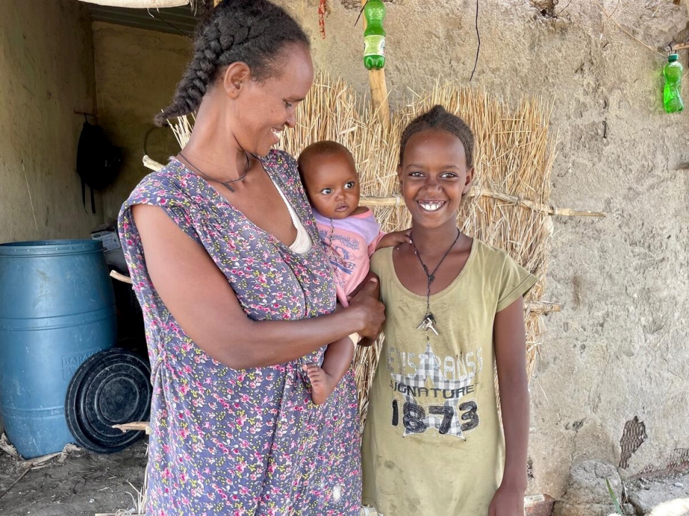 Sudan. Letha, Eymaret and baby Madher stand outside their home in Village 8 after being reunited.