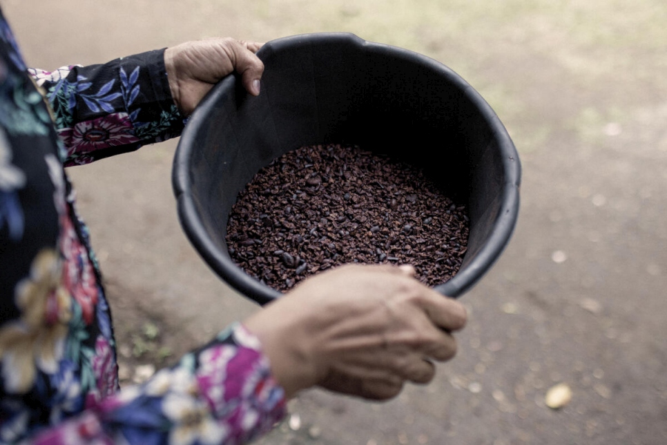 كارمن*، طالبة لجوء تبلغ من العمر 38 عاماً من نيكاراغوا، تحمل حبوب الكاكاو المجففة التي فصلتها عن قشورها - وهي خطوة واحدة في عملية تحويلها إلى شوكولا.