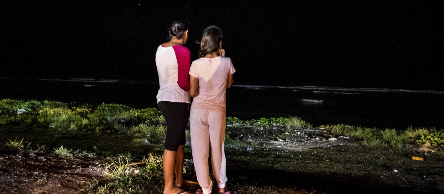 Night time. Two young women look out to sea.