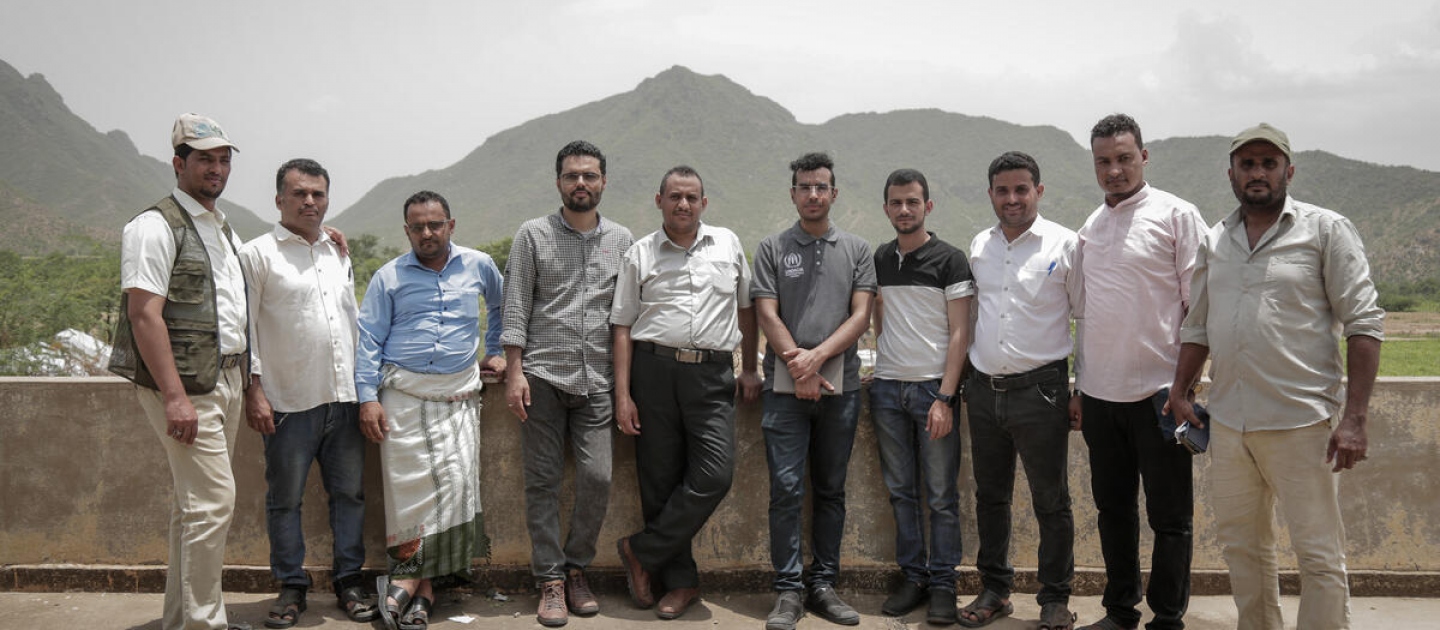 Ameen Jubran (centre, white shirt) and other Jeel Albena staff members from  staff stand with the UNHCR Yemen Representative in Al-Hudaydah